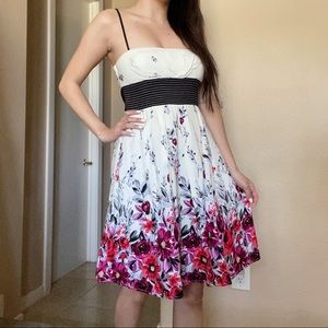 White and floral A-line dress with black tie in the back and spaghetti straps